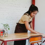 Myanmar maid cleaning a dining table with focus and care, representing professional domestic help services in Singapore.
