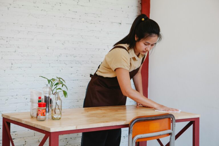 Myanmar maid cleaning a dining table with focus and care, representing professional domestic help services in Singapore.