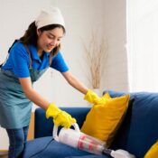 A domestic helper vacuuming the dirt out of sofa.