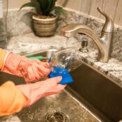 Domestic helper washing a glass at the kitchen sink, highlighting essential household support for busy working families in Singapore.