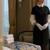 Professional housekeeper in formal uniform standing in a well-prepared hotel room—representing how maid recruitment agencies in Singapore ensure quality and trust.
