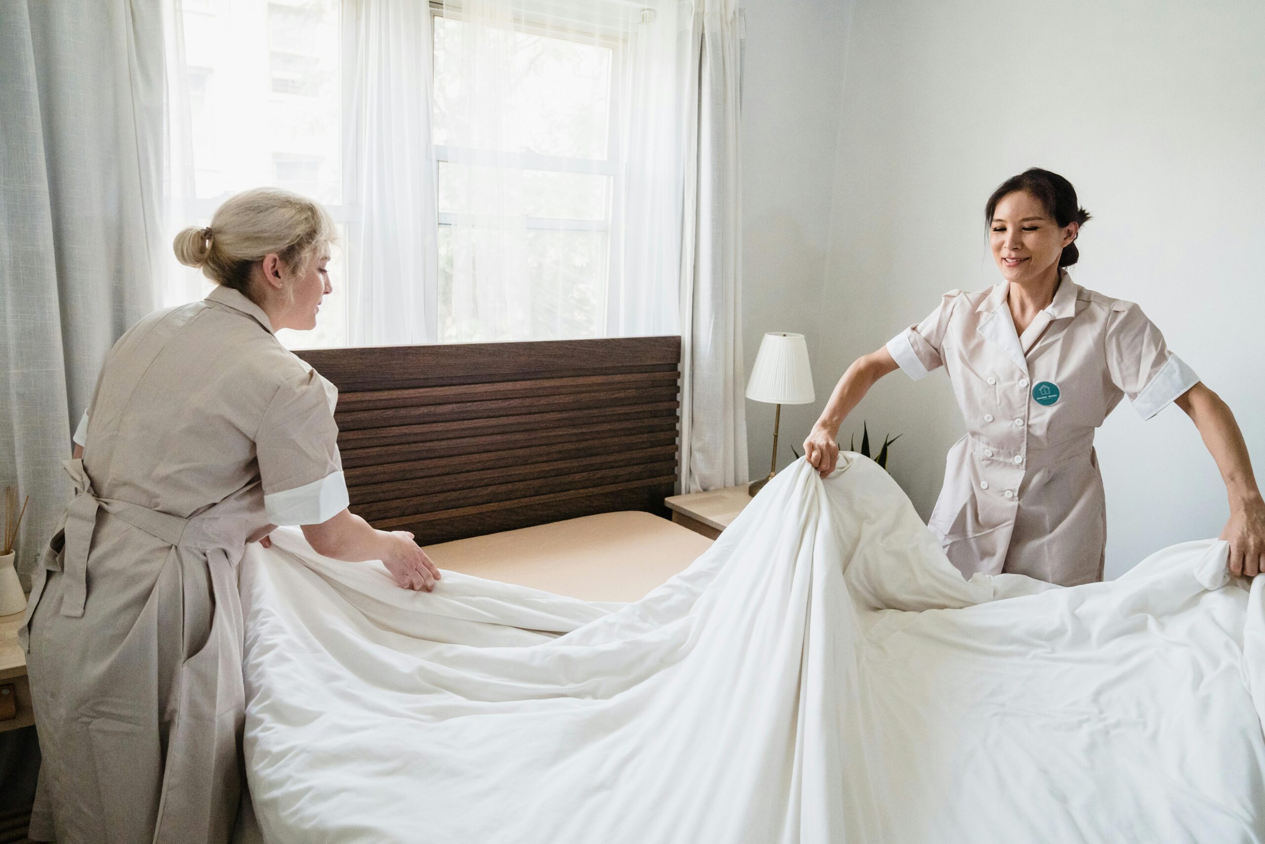 Two maids making a bed together, illustrating the difference between hiring a transfer maid or a new helper for household needs in Singapore.